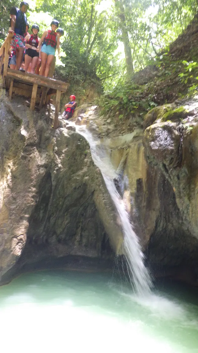 A natural waterfall cascade in the Dominican Republic with people sliding down the rocks